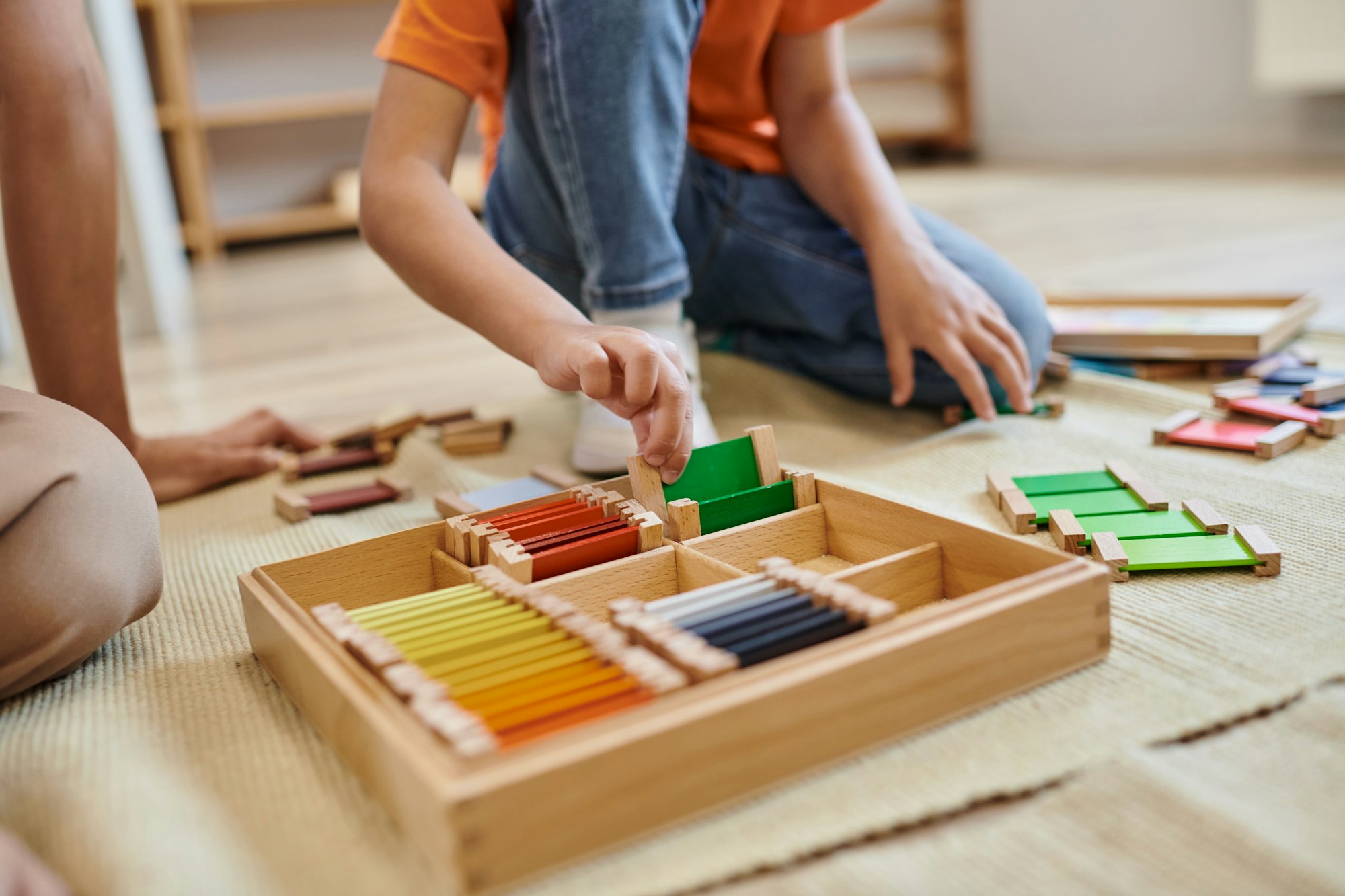 montessori school concept, cropped view of girl playing color matching game near teacher, play based